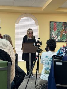 achel Manley, Governor General’s Award–winning author, stands at a podium inside the Jamaican Consulate General in Toronto, reading an excerpt from her book “George The Last” during its 2025 launch event.